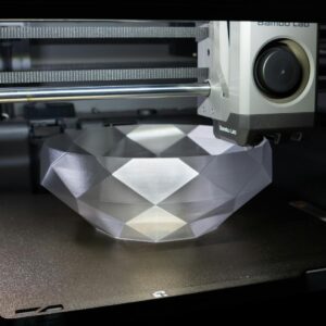 A 3D printer creating a geometric crystal-like bowl in a modern setup.